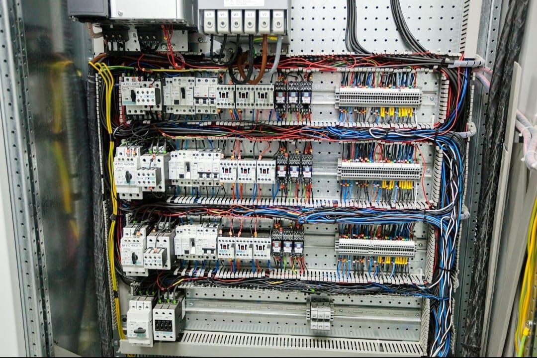 Close-up of a control panel showing organised wiring, contactors and terminal blocks